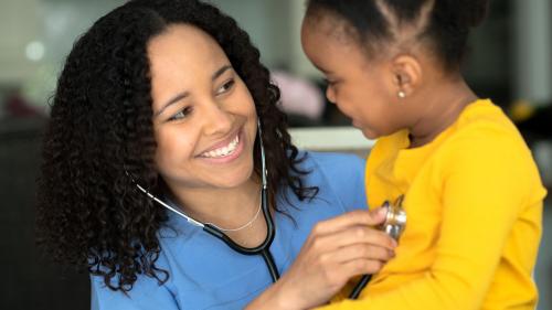 School nurse holds stethoscope to child's heart