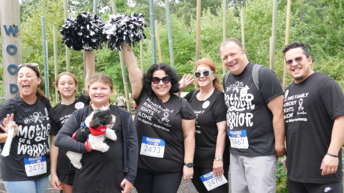 group of people in matching black t shirts, holding pom-poms